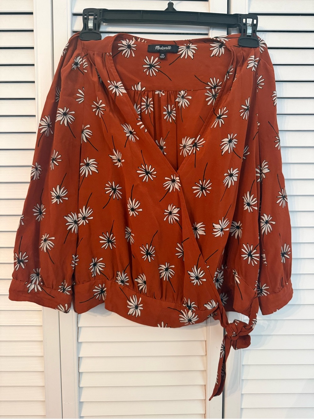 Madewell silk wrap top features a rust-colored fabric with a white daisy size XS